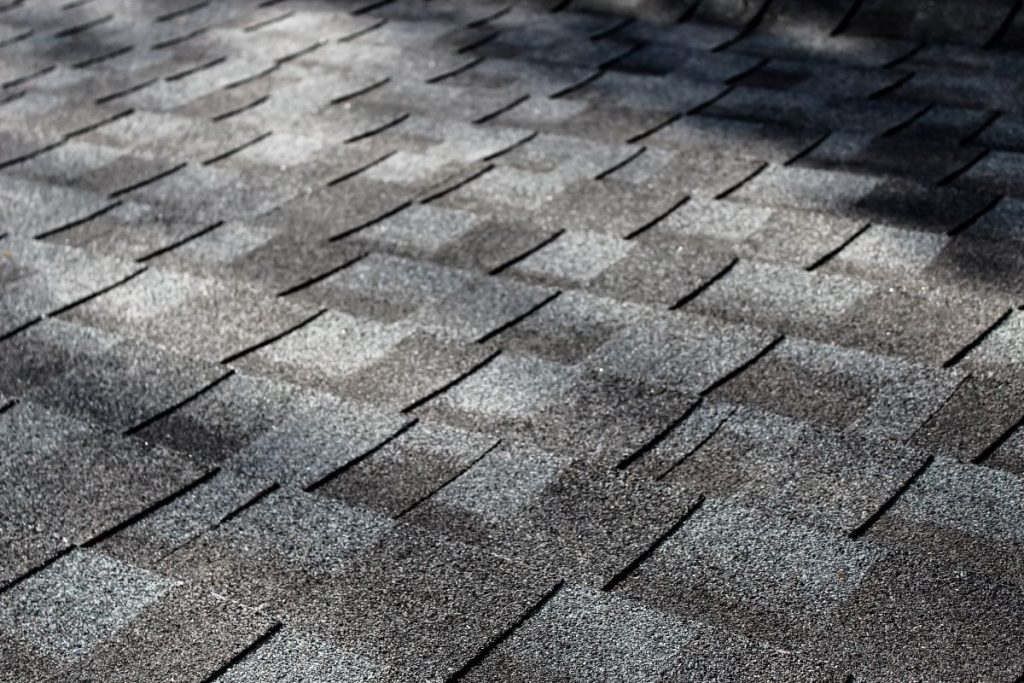 close-up of an asphalt shingle roof at an angle with dappled sunlight